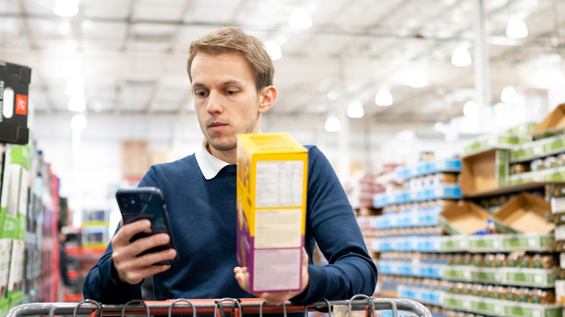 man looking at calculator grocery