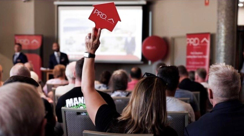 woman raising prd red paddle at an auction 2