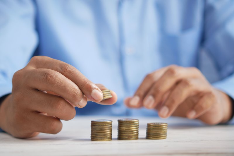 man wearing blue shirt stacking coins